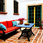 **

A sun-drenched patio in Seville, Spain. Terracotta tile flooring creates a warm, inviting space. Wrought-iron furniture with colorful cushions sits around a small, mosaic-tiled table. Potted geraniums and bougainvillea add vibrant splashes of color. Late afternoon light casts long shadows, highlighting the textures of the tile and the whitewashed walls in the background. Fully clothed people in casual, modest attire are enjoying tapas and conversation. Safe for work, appropriate content, family-friendly. Perfect anatomy, correct proportions, natural pose, well-formed hands, proper finger count, professional photography, high quality.

**
